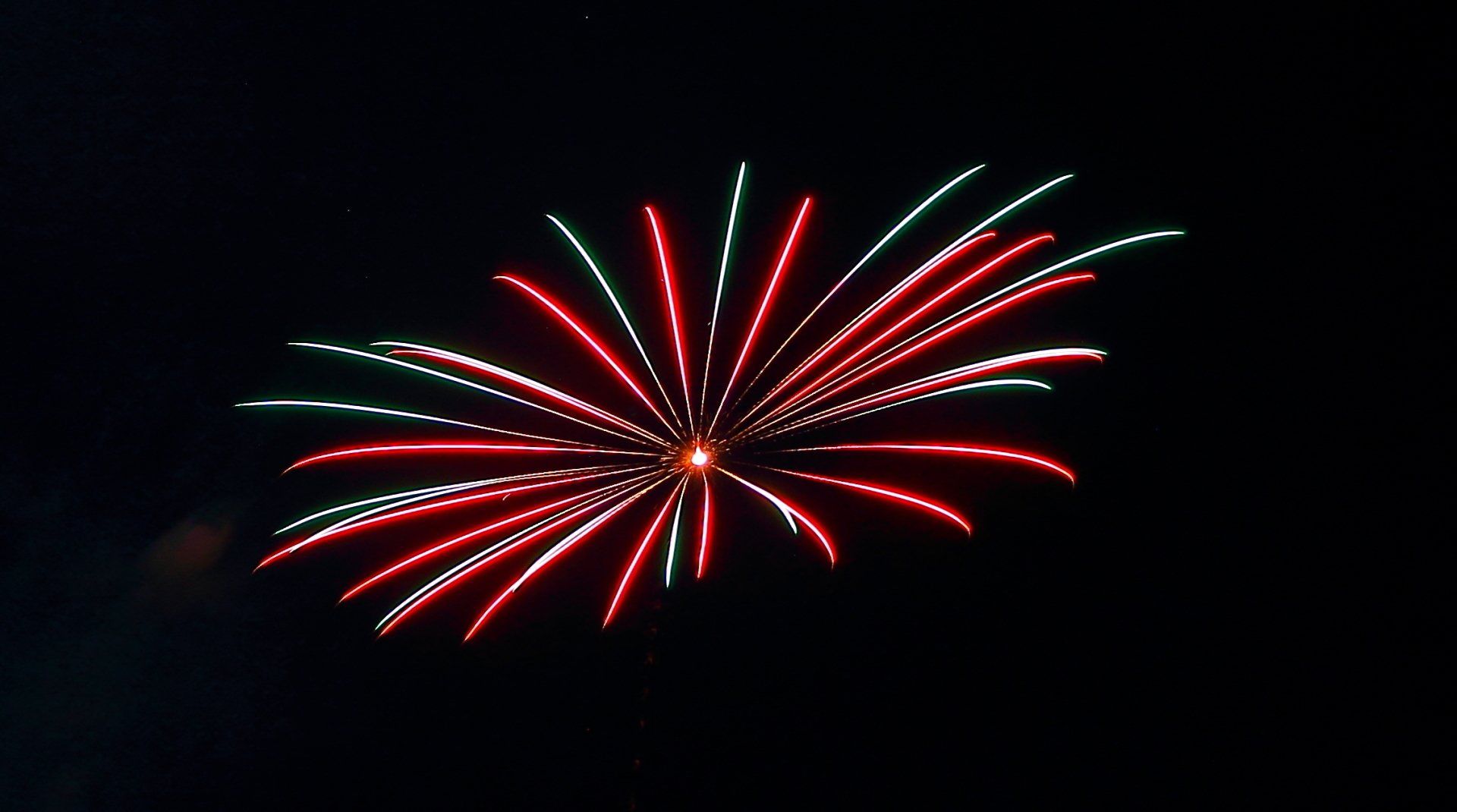 A red white and green fireworks display in the night sky