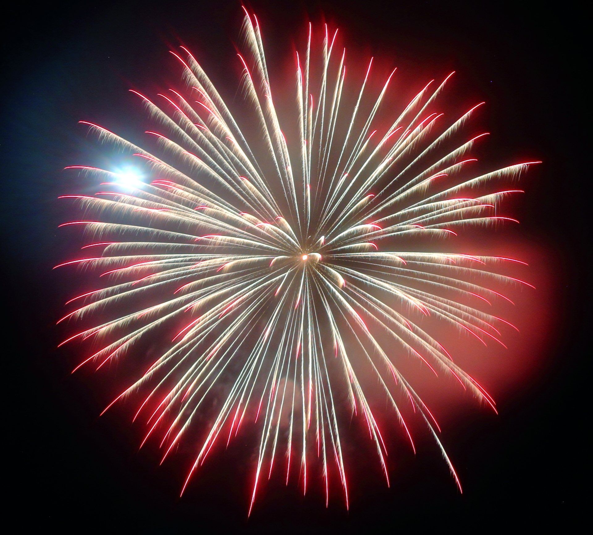 A red and white fireworks display in the night sky