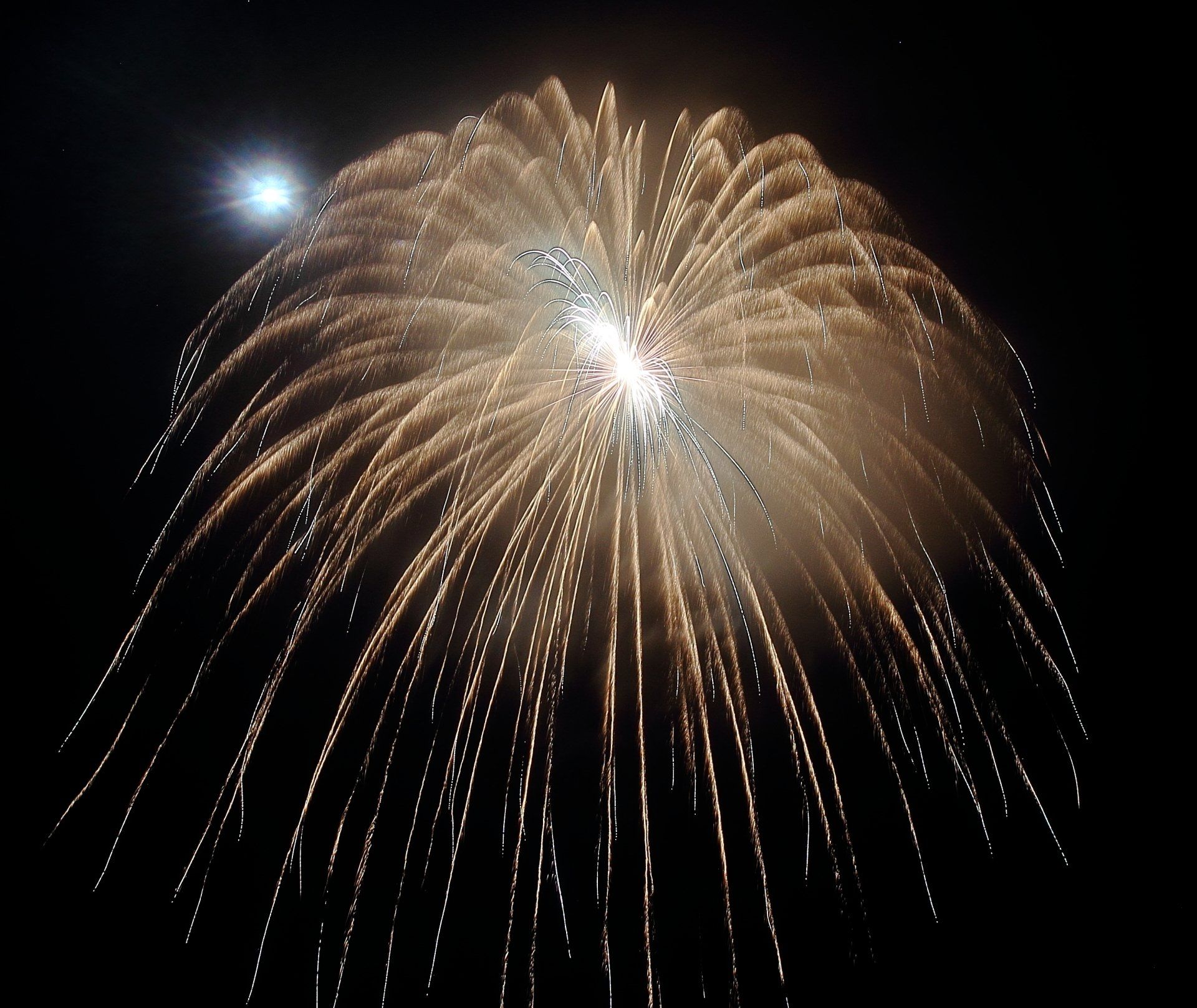A fireworks display with the moon in the background