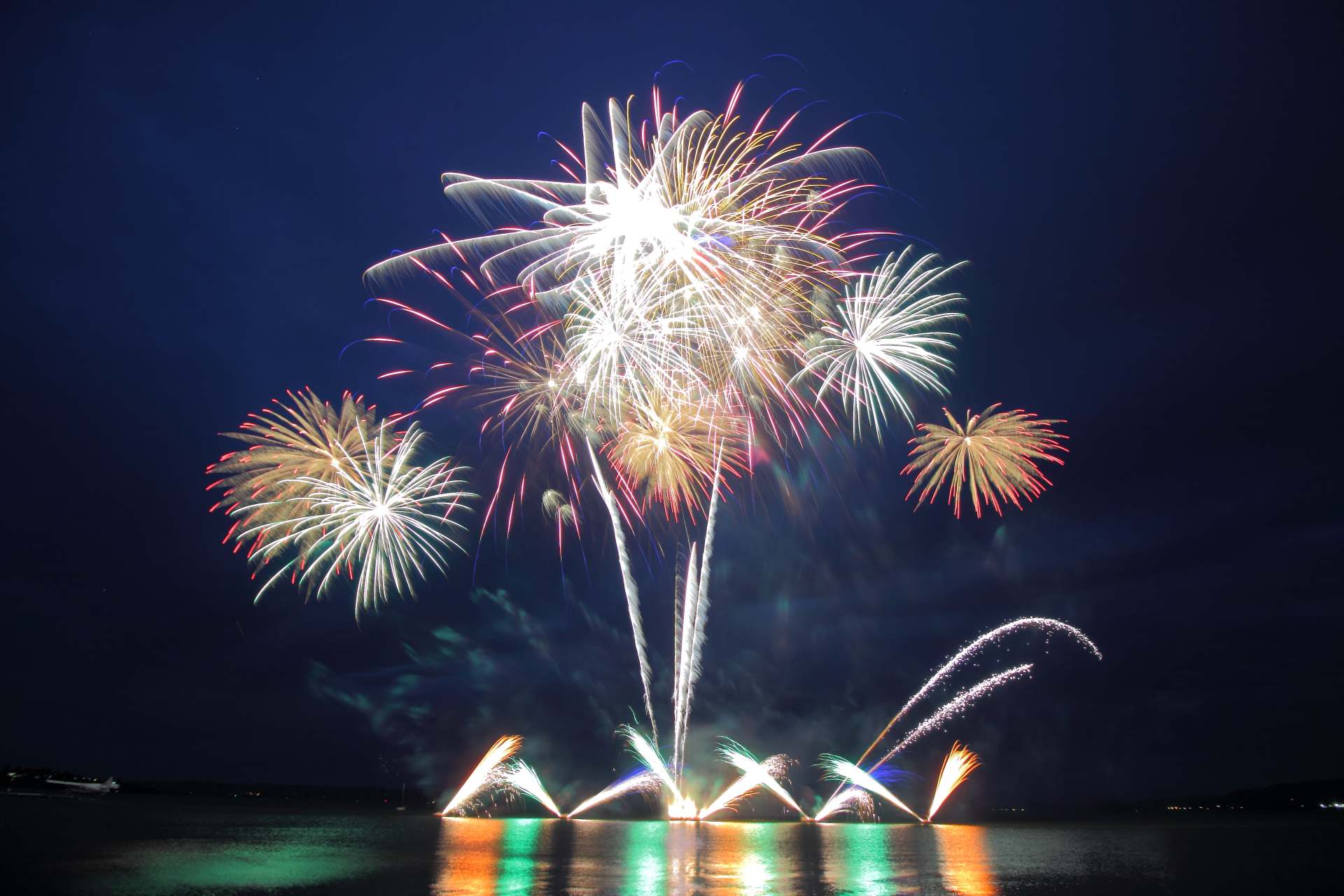 A fireworks display over a body of water at night