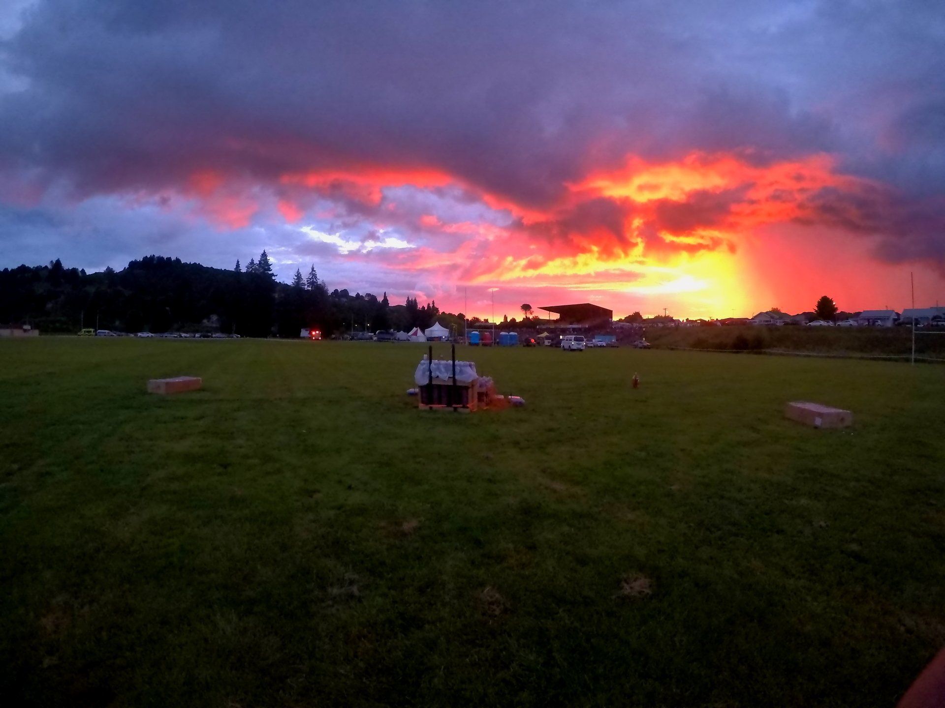 A sunset over a grassy field with a lot of clouds