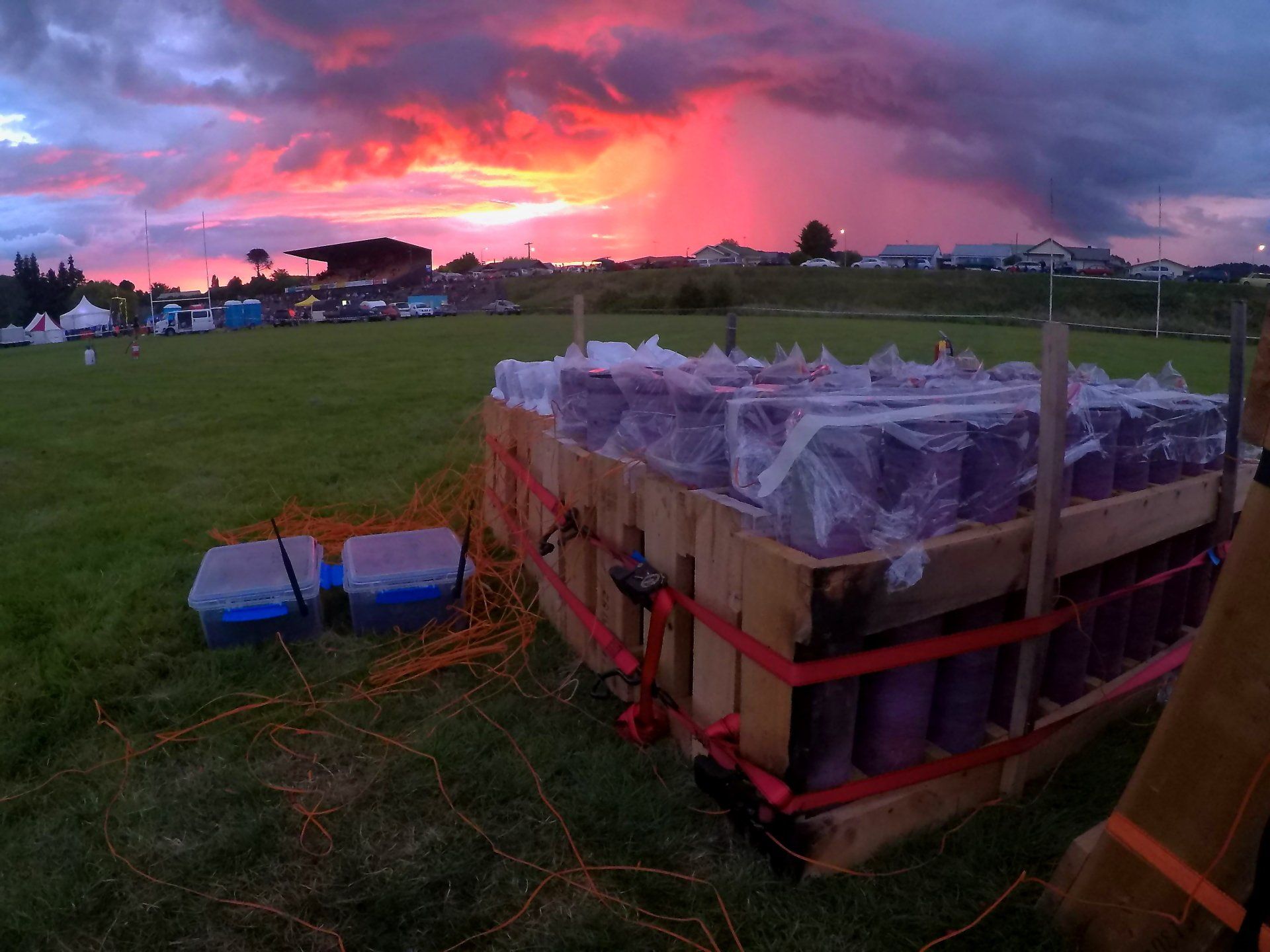 A fireworks display is being prepared in a field with a sunset in the background.