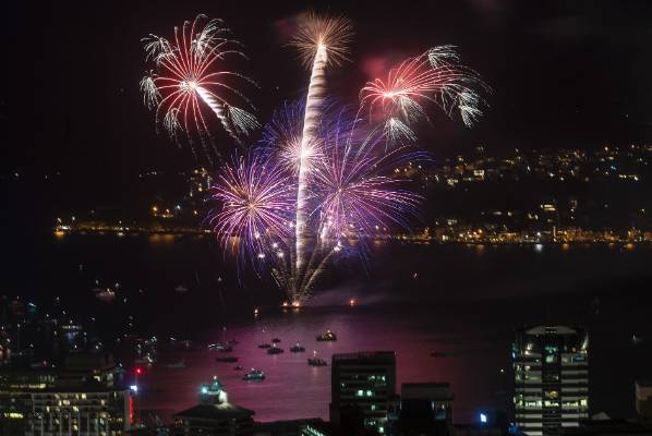 A fireworks display over a body of water in a city