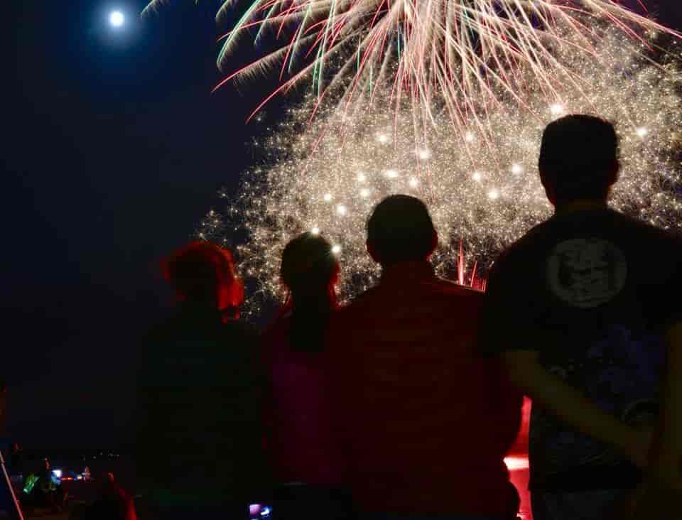 A group of people are watching fireworks in the night sky.
