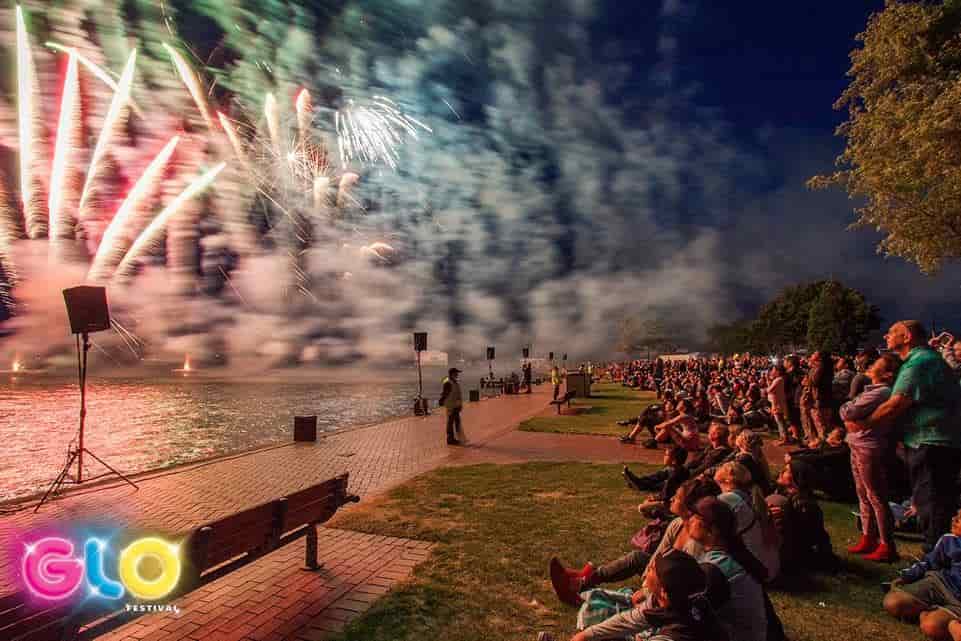 A crowd of people are watching fireworks over a body of water.