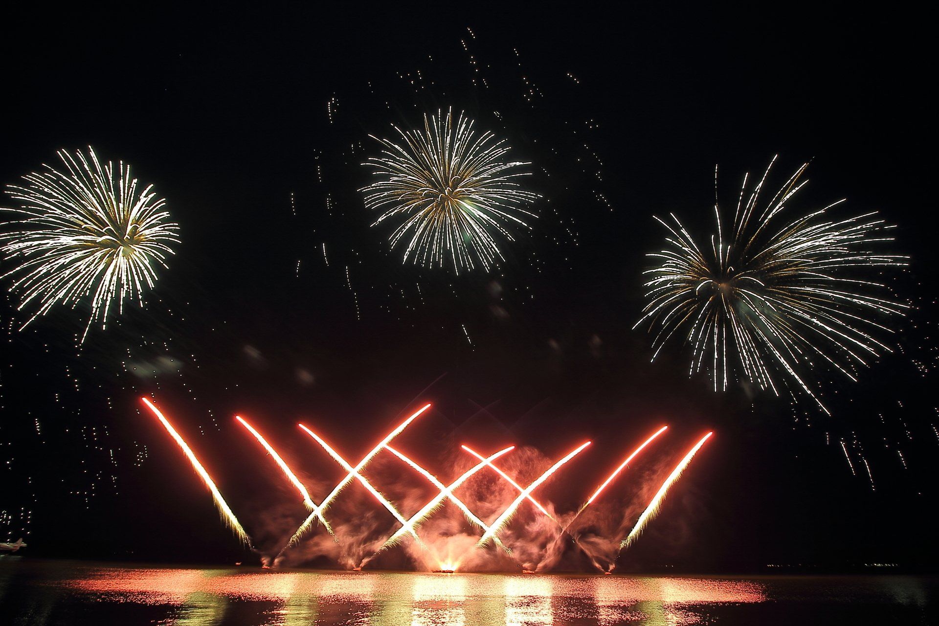Fireworks are displayed over a body of water for NYE in Rotorua glo festival