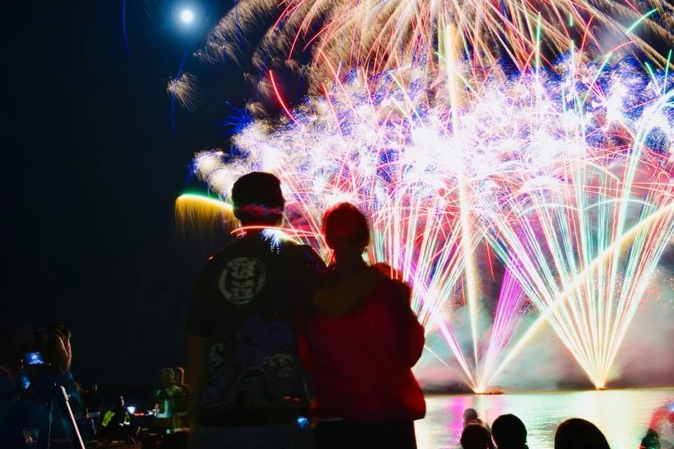 A man and a woman are watching fireworks over the Rotorua Lake for NYE