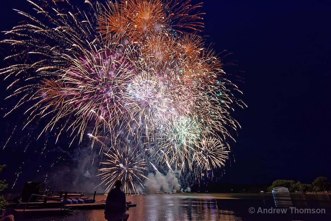 A person is watching a fireworks display over a body of water in rotorua
