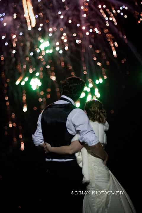A bride and groom are watching fireworks at their wedding