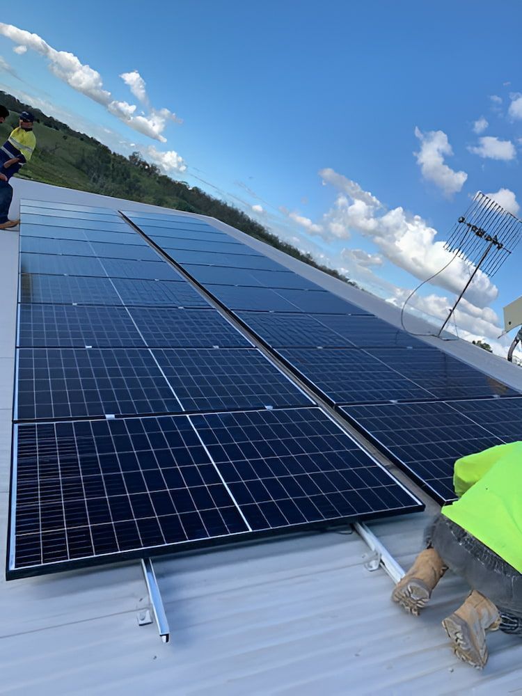 A Row Of Solar Panels Are Being Installed On The Roof Of A Building — Levi's Electrics in Yeppoon, QLD