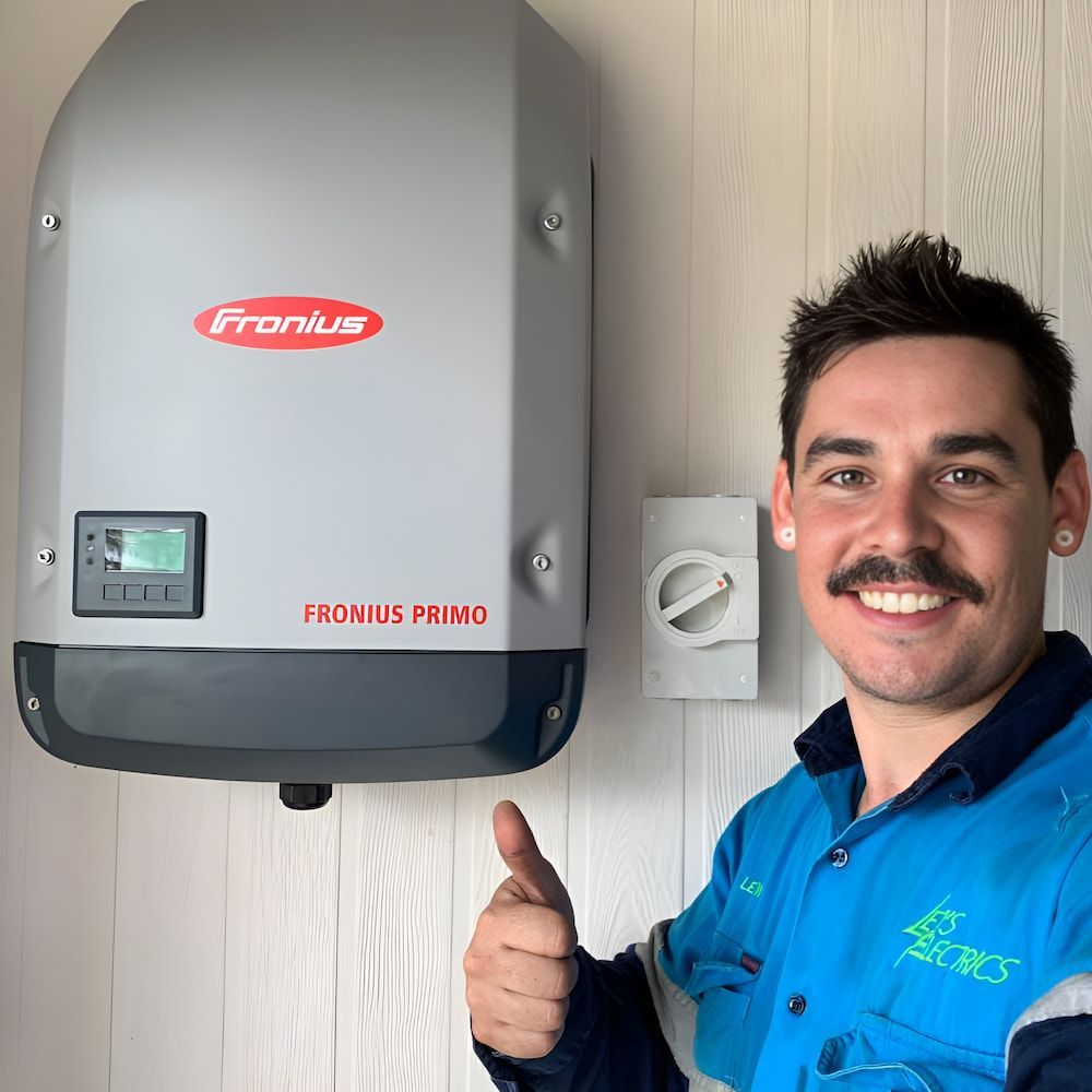 A Man Is Giving A Thumbs Up In Front Of A Fronius Inverter — Levi's Electrics in Nerimbera, QLD