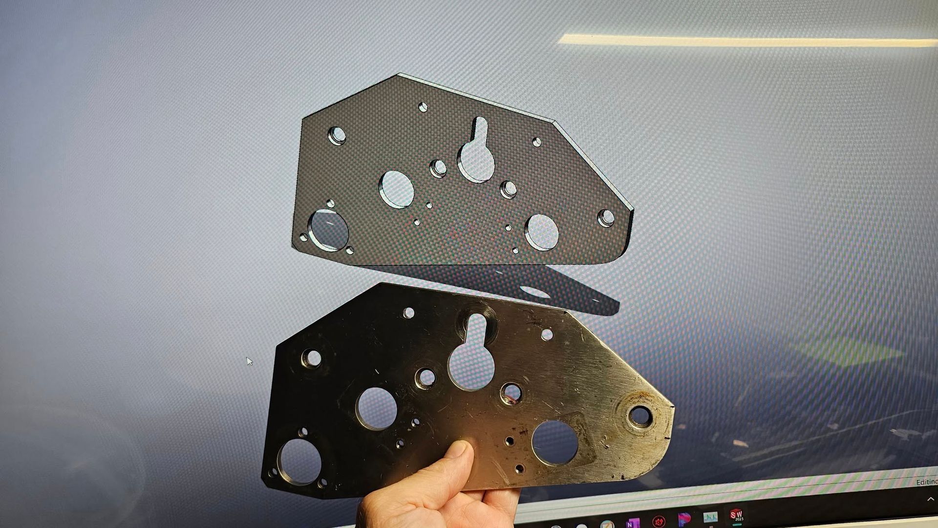 Two metal plates with holes, one held, one above.