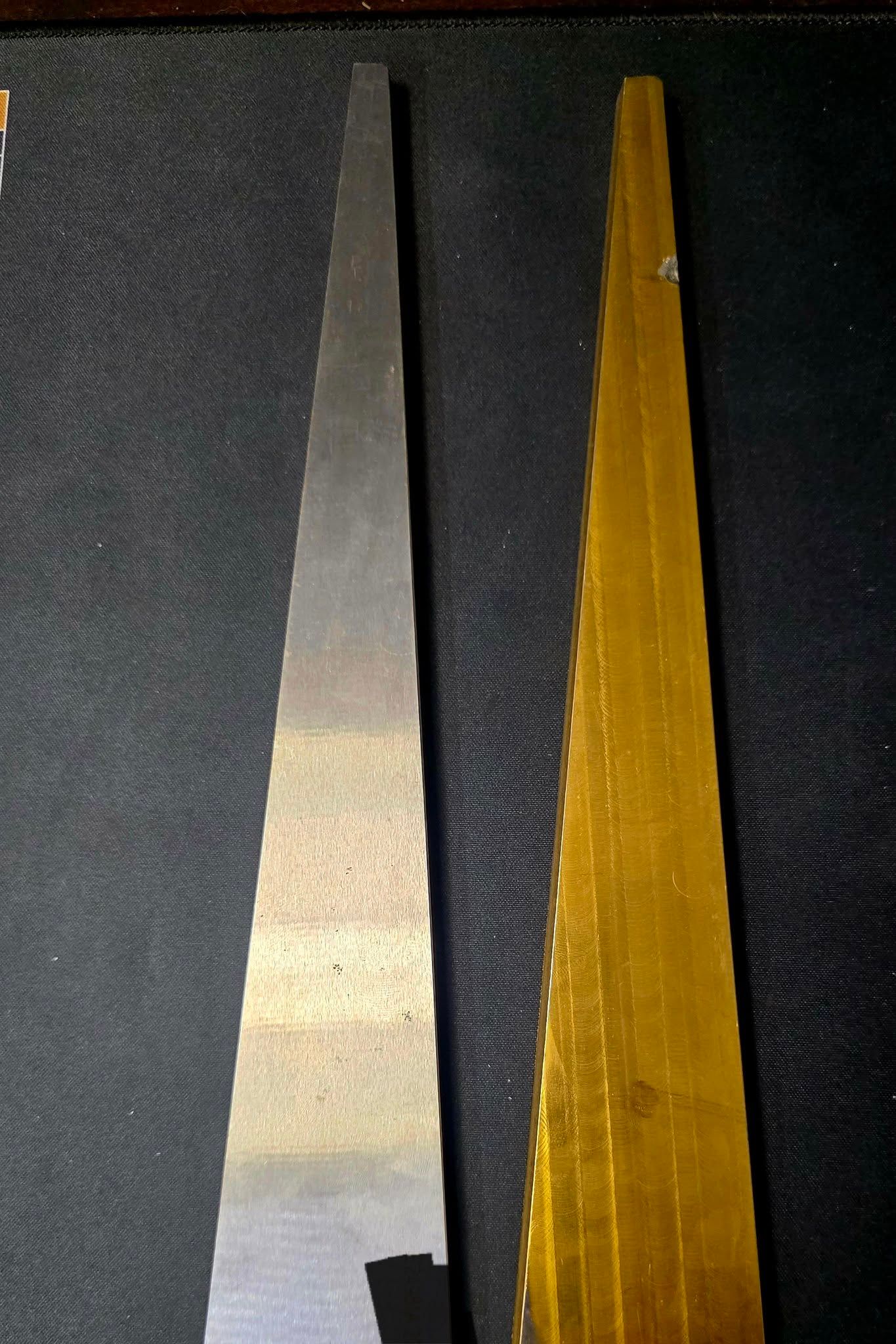 Two flat, triangular metal pieces; one silver, one gold.