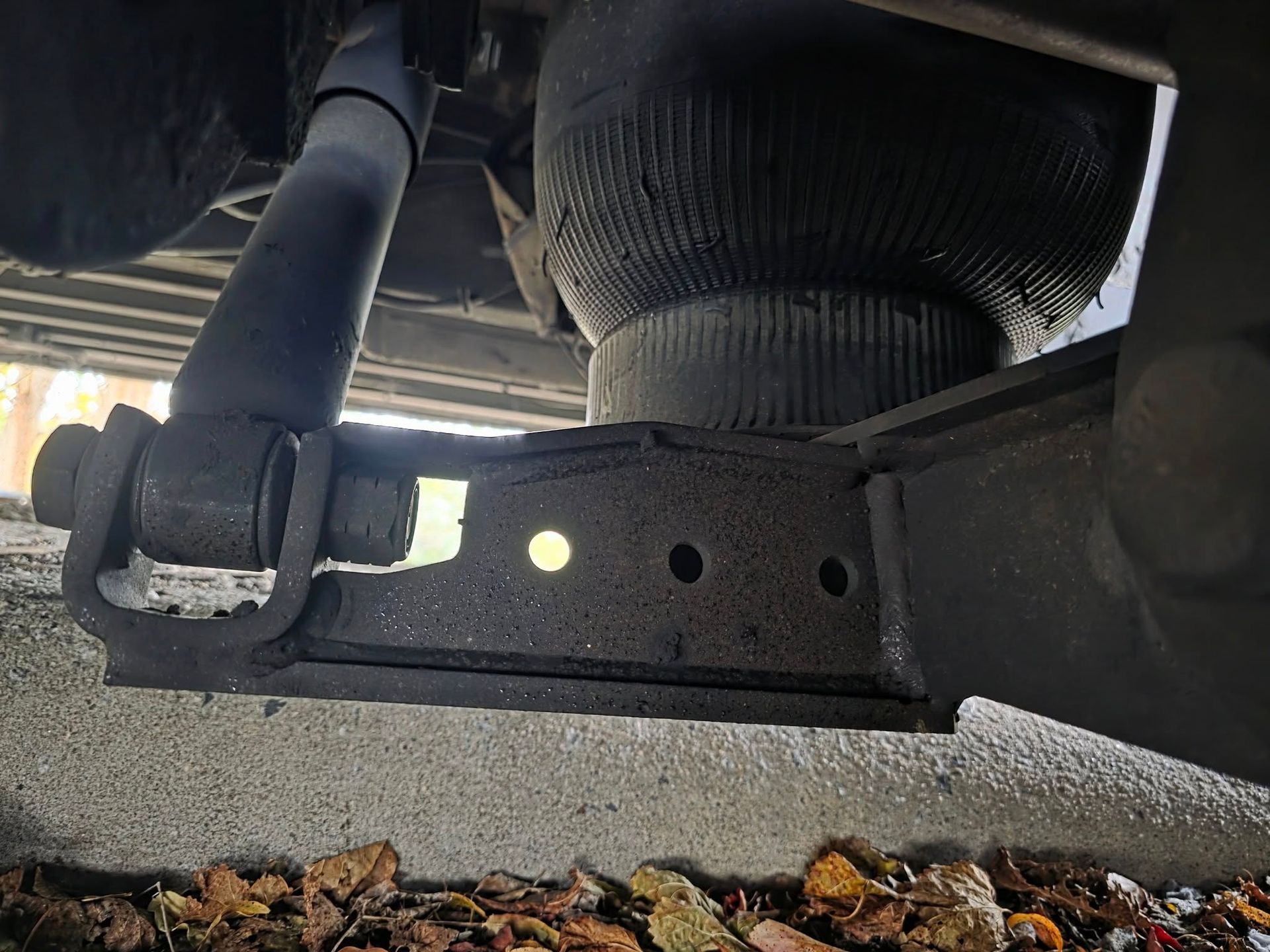 Close-up view of a vehicle's suspension system showing a shock absorber, air spring, and mounting bracket.