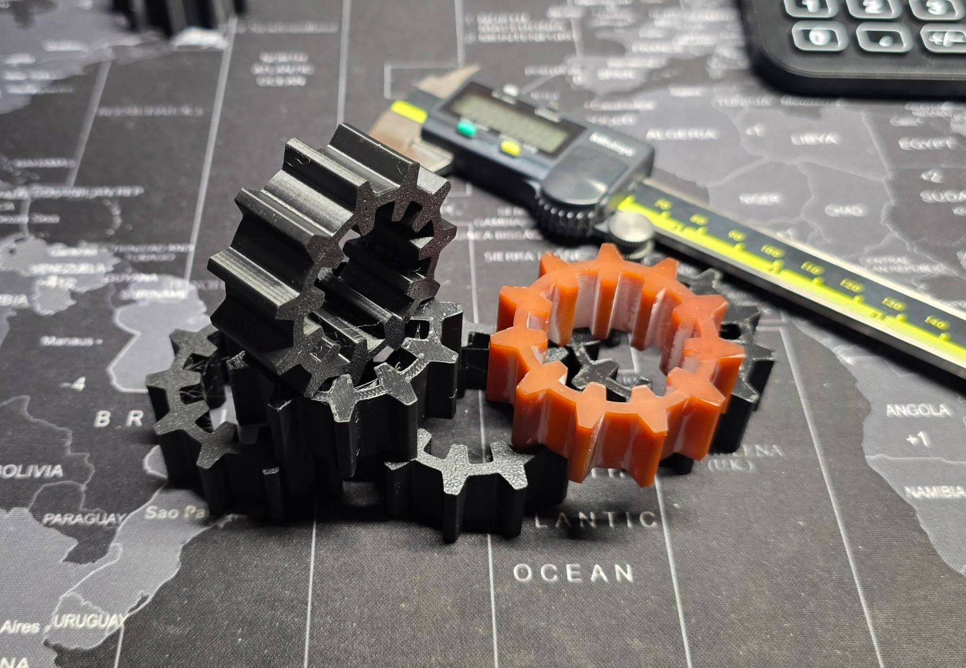 Black and orange gears and calipers on a world map.