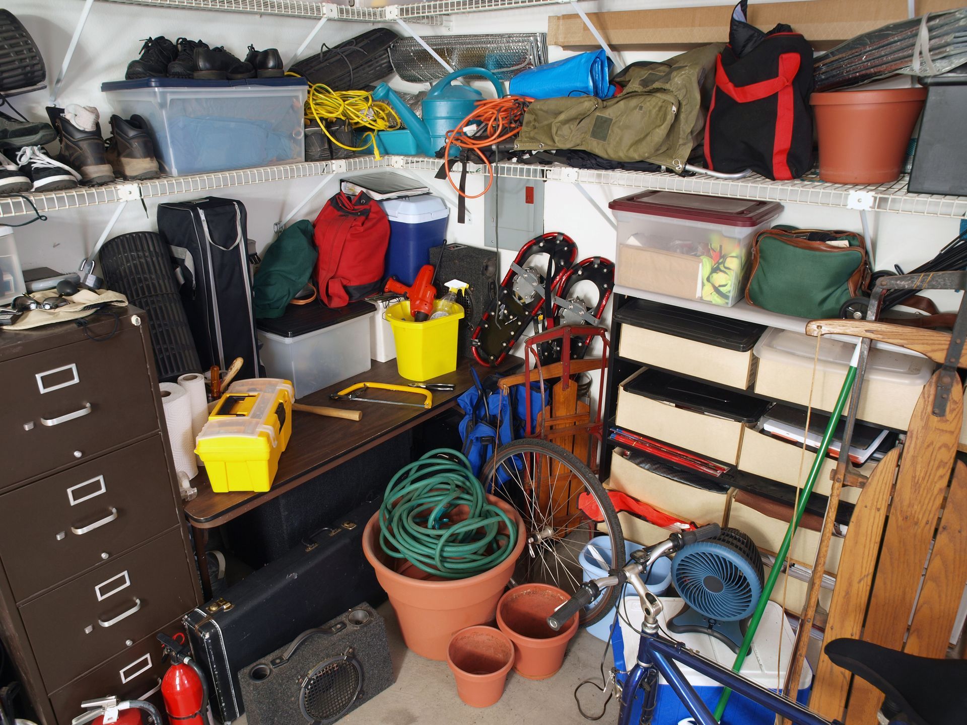 Cluttered garage filled with storage bins, tools, and equipment.