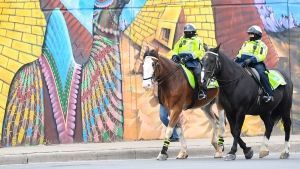 Police officers ride their horses past a mural on Earth Day during the COVID-19 pandemic in Toronto