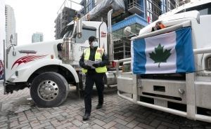 A police officer walks between parked trucks as he distributes a notice to protesters