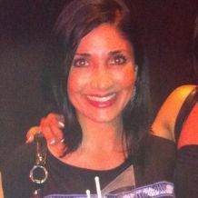 Woman with dark hair smiling, holding a keychain; close-up.