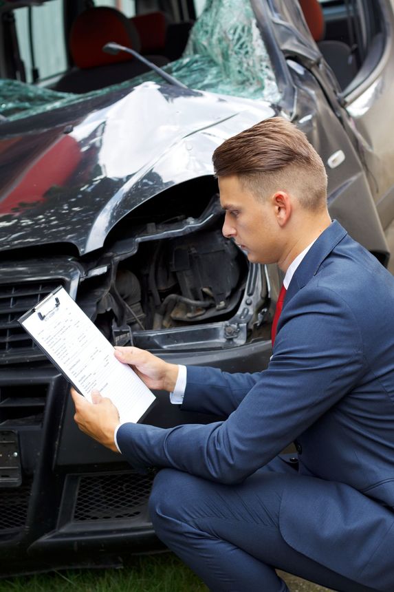 Insurance assessor inspecting damaged vehicle.