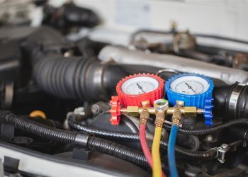 A close up of a car engine with two gauges attached to it.