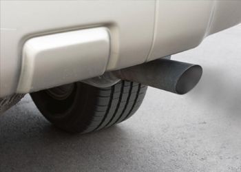 A close up of a car exhaust pipe with smoke coming out of it.