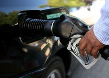 A man is pumping gas into a car at a gas station