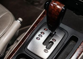 A close up of a car 's shifter with a wooden handle.