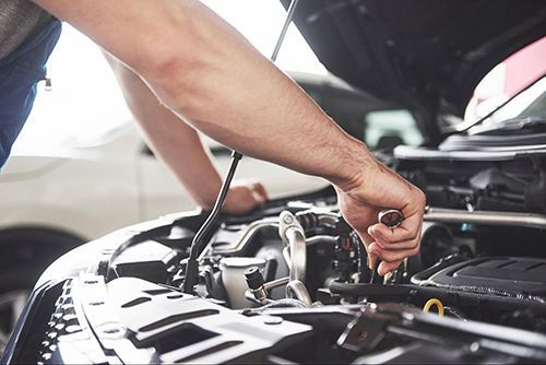 A man is working on the engine of a car.