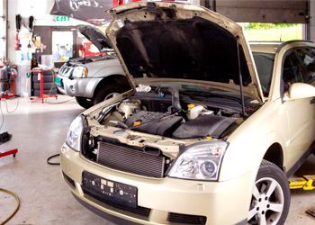 A car is being worked on in a garage with the hood open