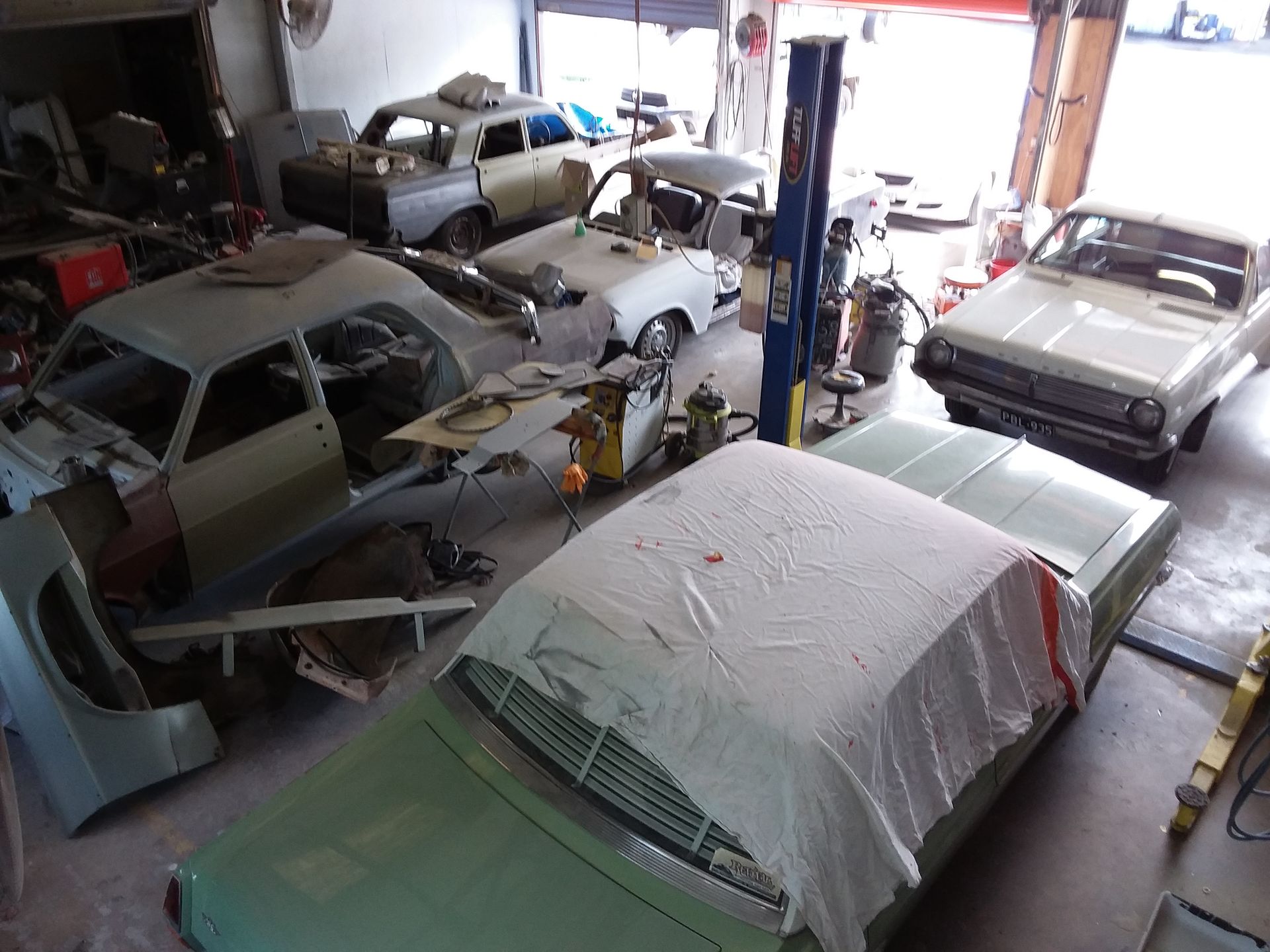 A green car door is being spray painted in a workshop — Proserpine Smash Repairs & Restorations In Proserpine, QLD