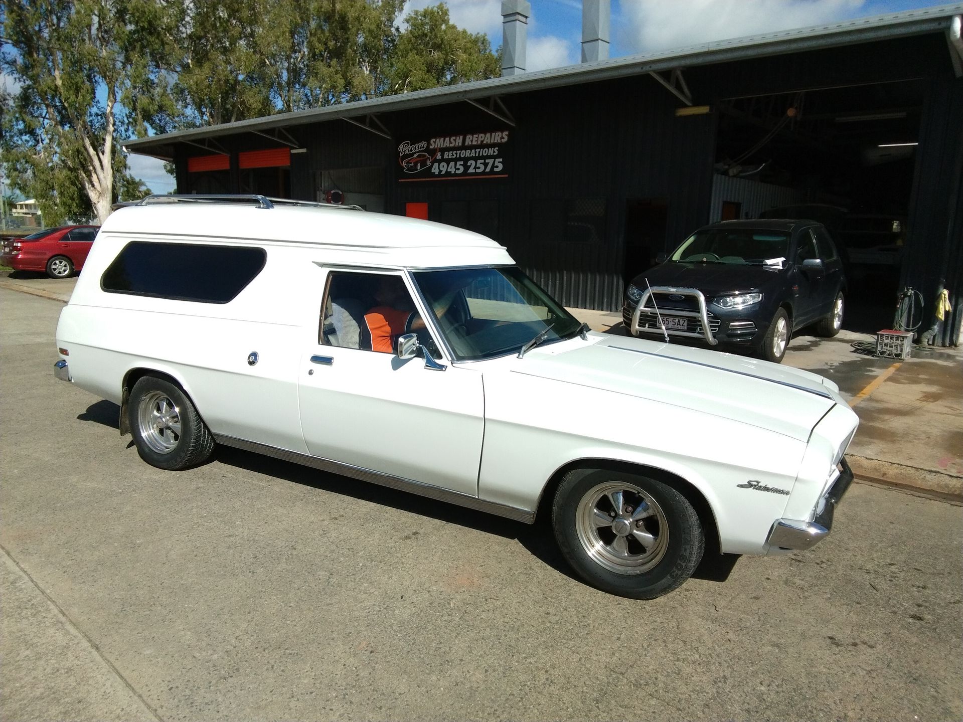 A Man Is Standing Next To A Black Car — Proserpine Smash Repairs & Restorations In Proserpine, QLD