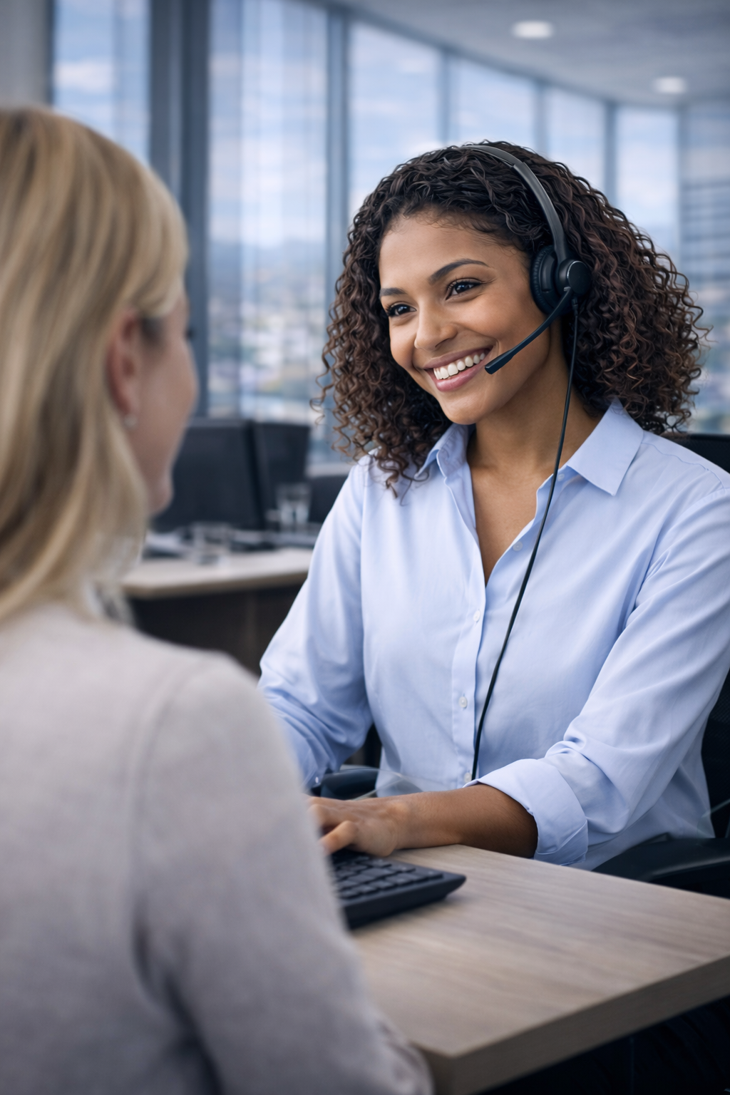 Woman with headset smiles at another woman, possibly providing customer service.