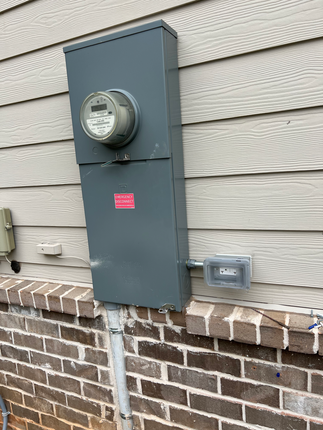 There is a meter on the side of a brick building.