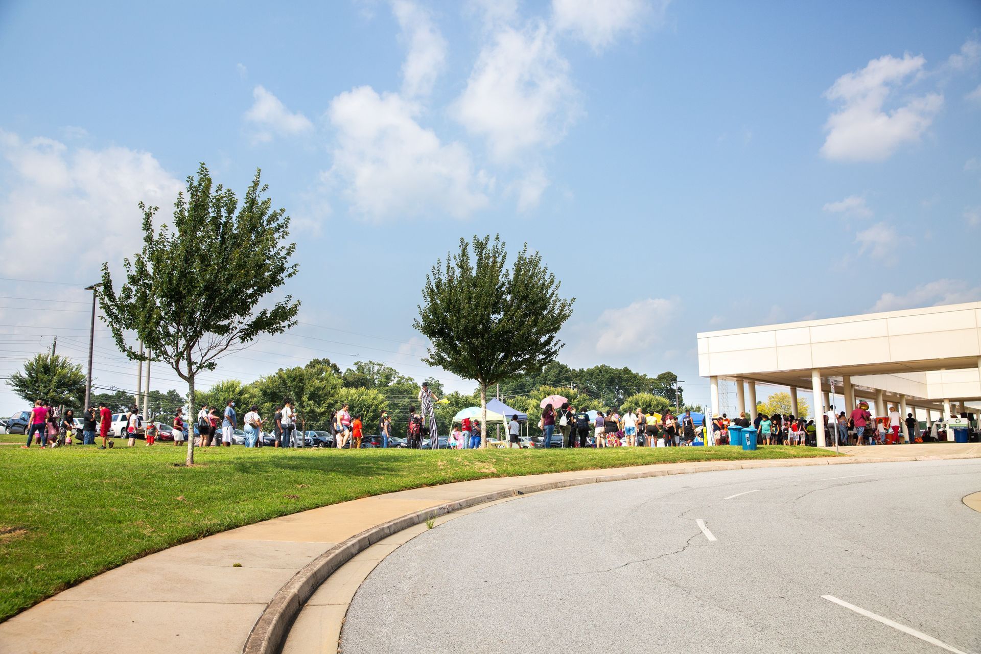 A group of people are gathered outside of a building on a sunny day.