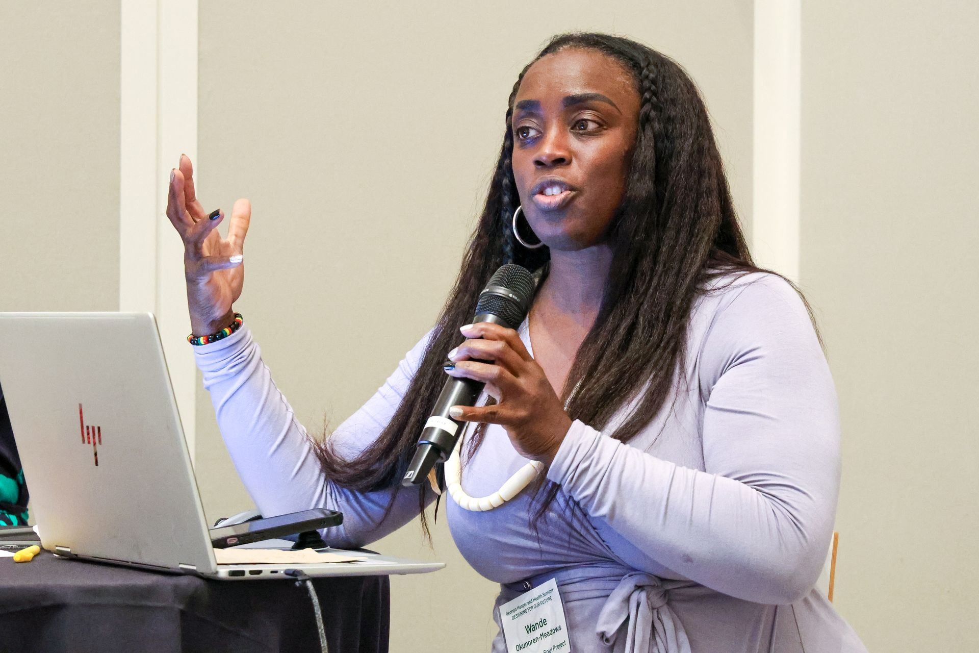 A woman is holding a microphone in front of a laptop computer.