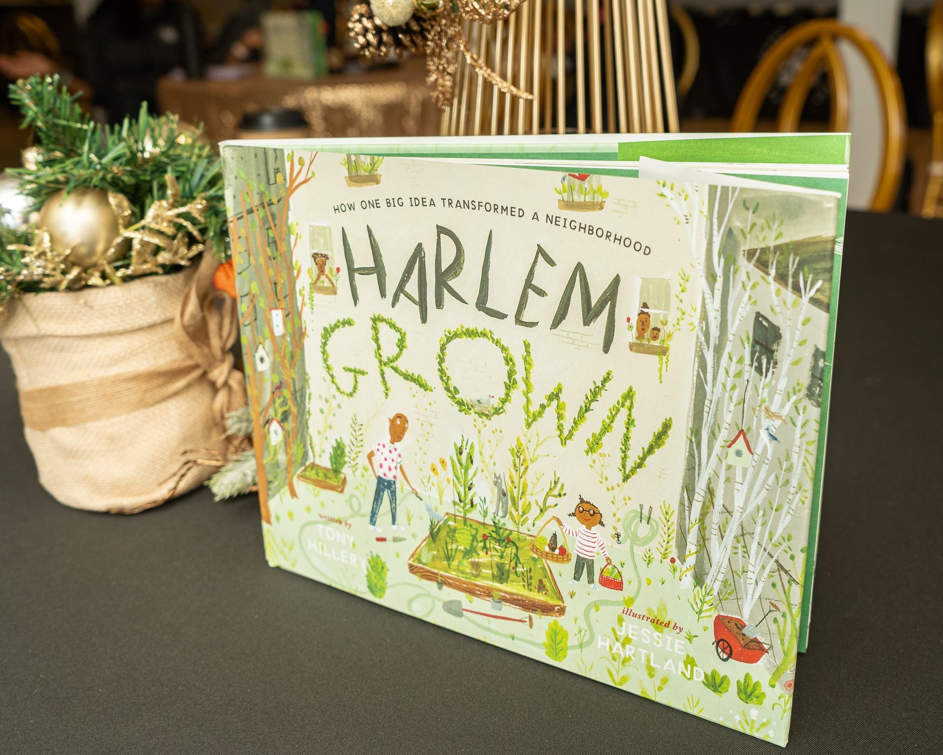 A book called harlem grown is sitting on a table next to a potted plant.