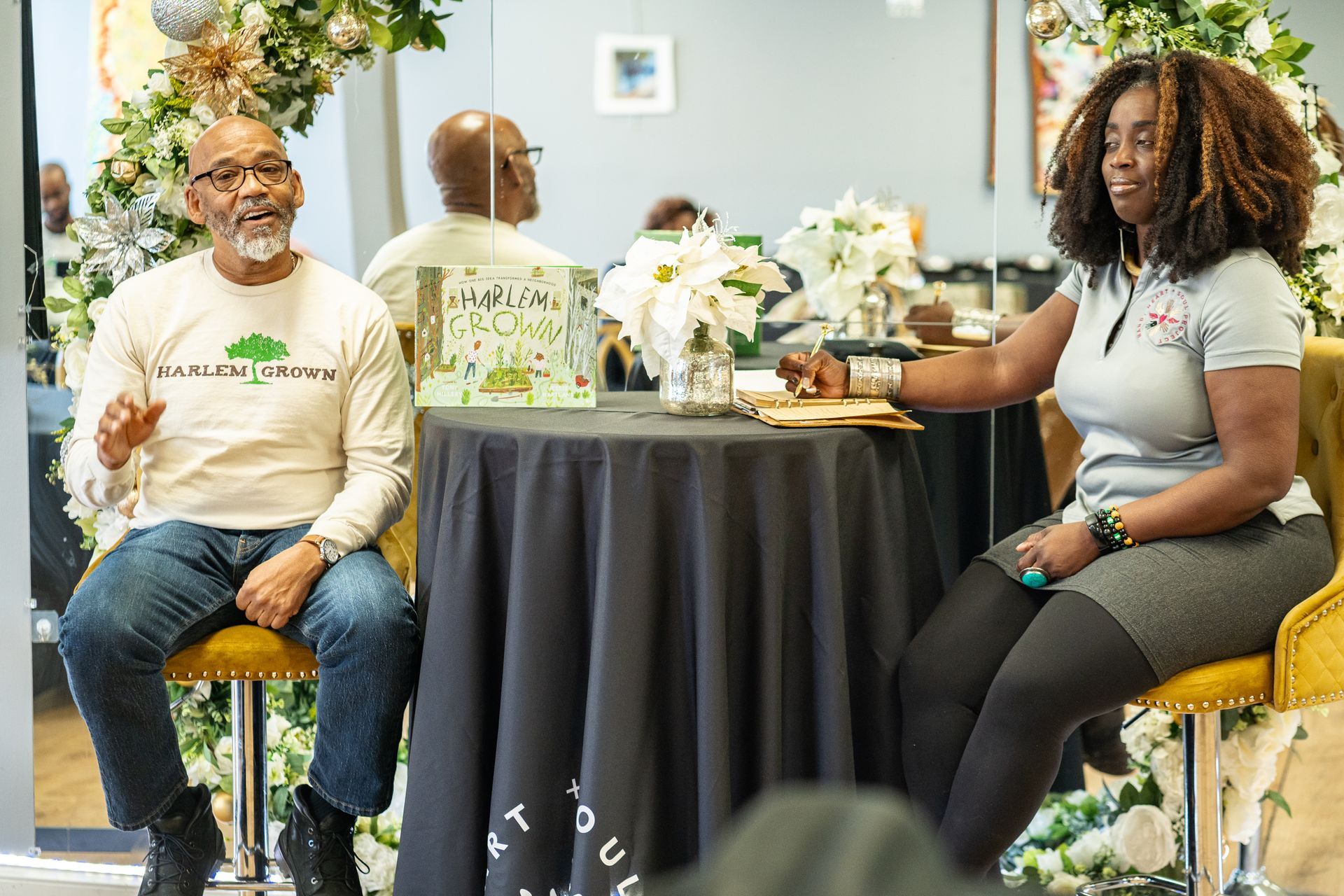 A man and a woman are sitting at a table talking to each other.