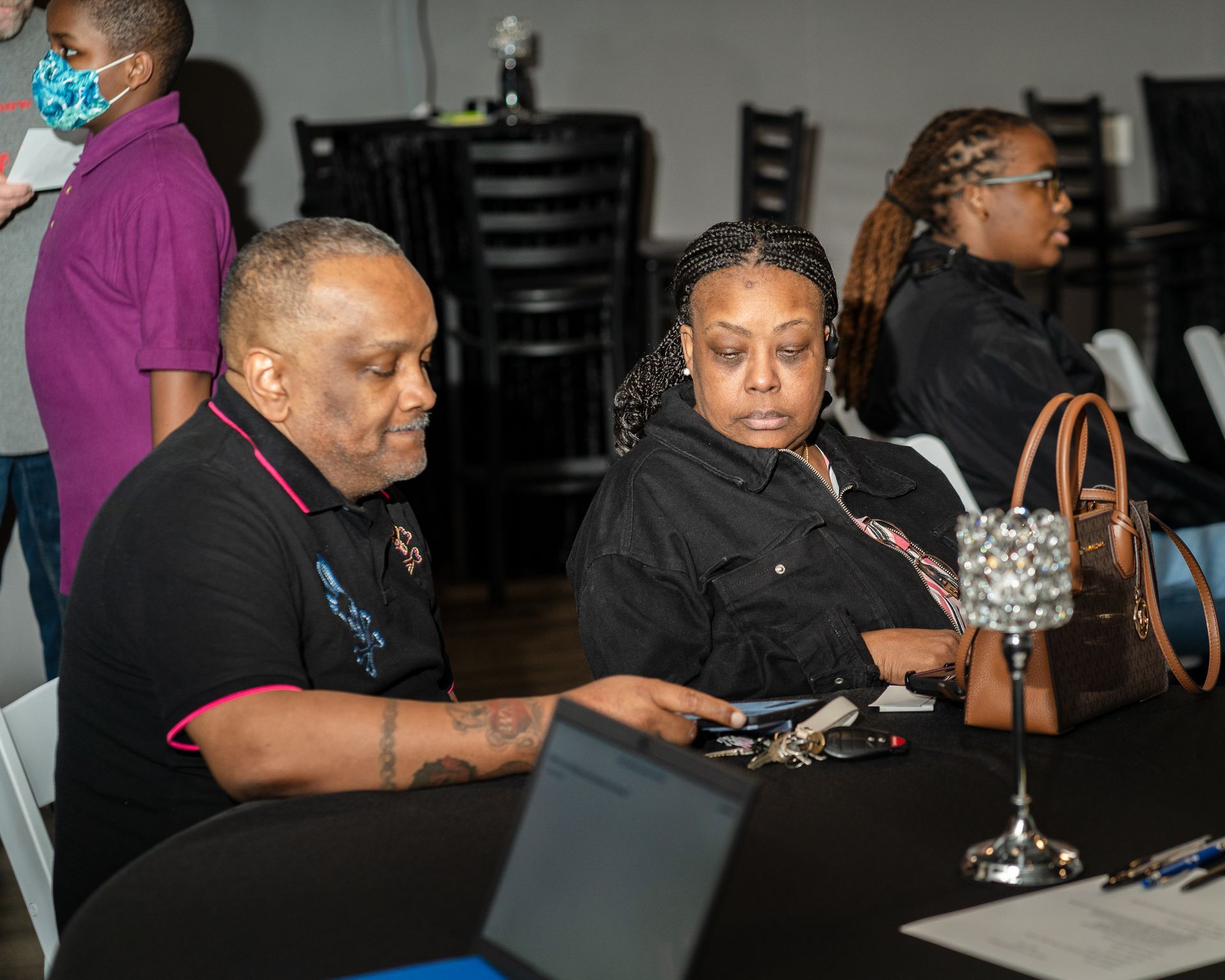 A man and a woman are sitting at a table with a laptop.