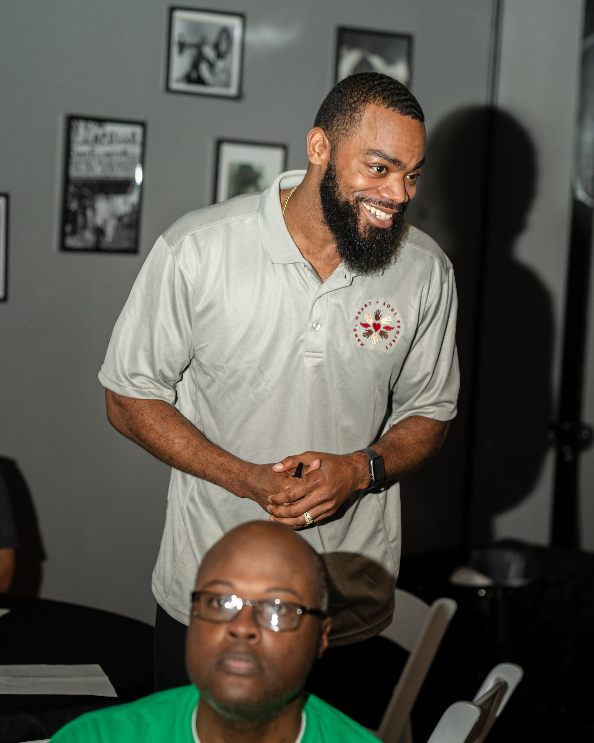 A man with a beard is standing next to another man with glasses