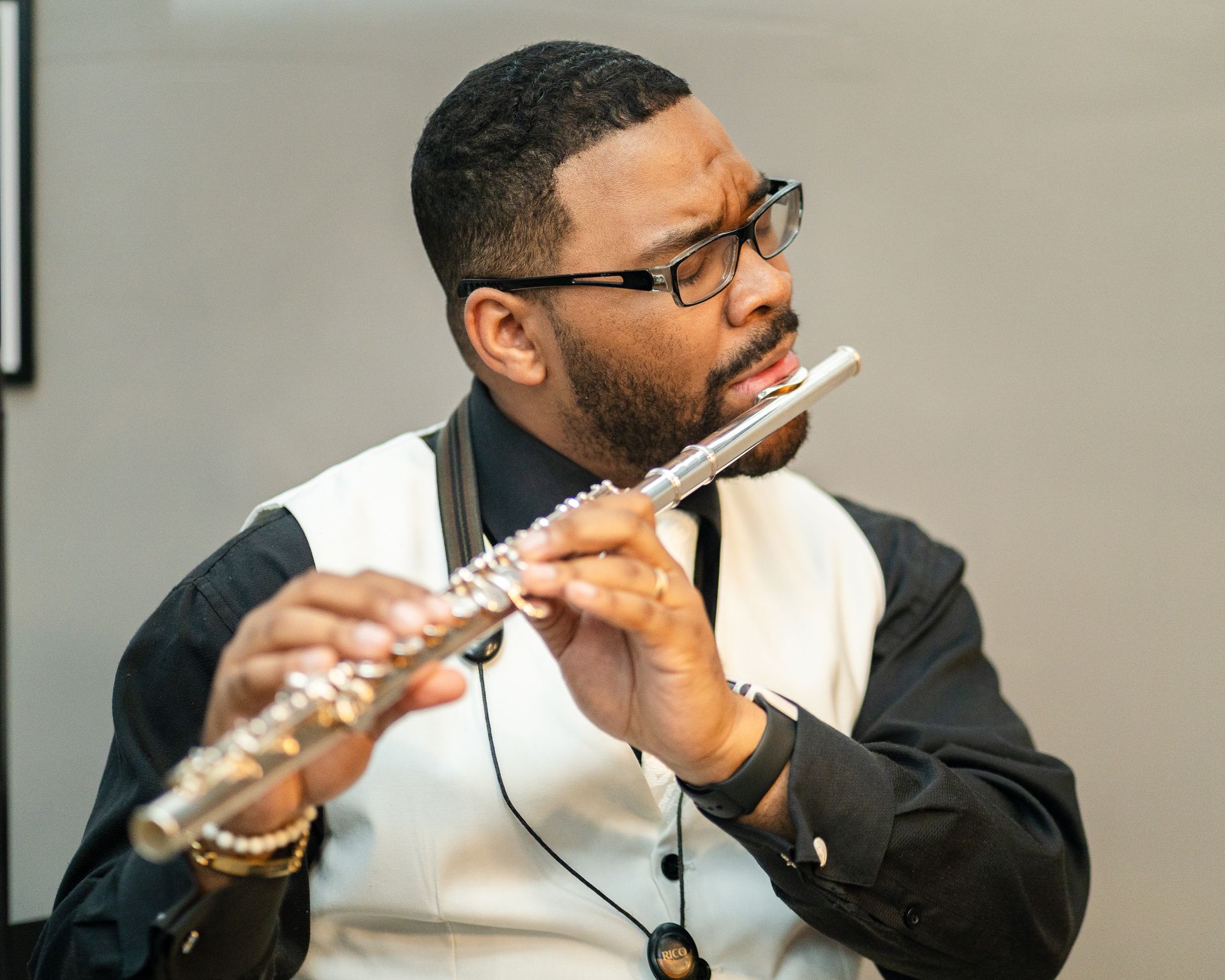 A man wearing glasses is playing a flute