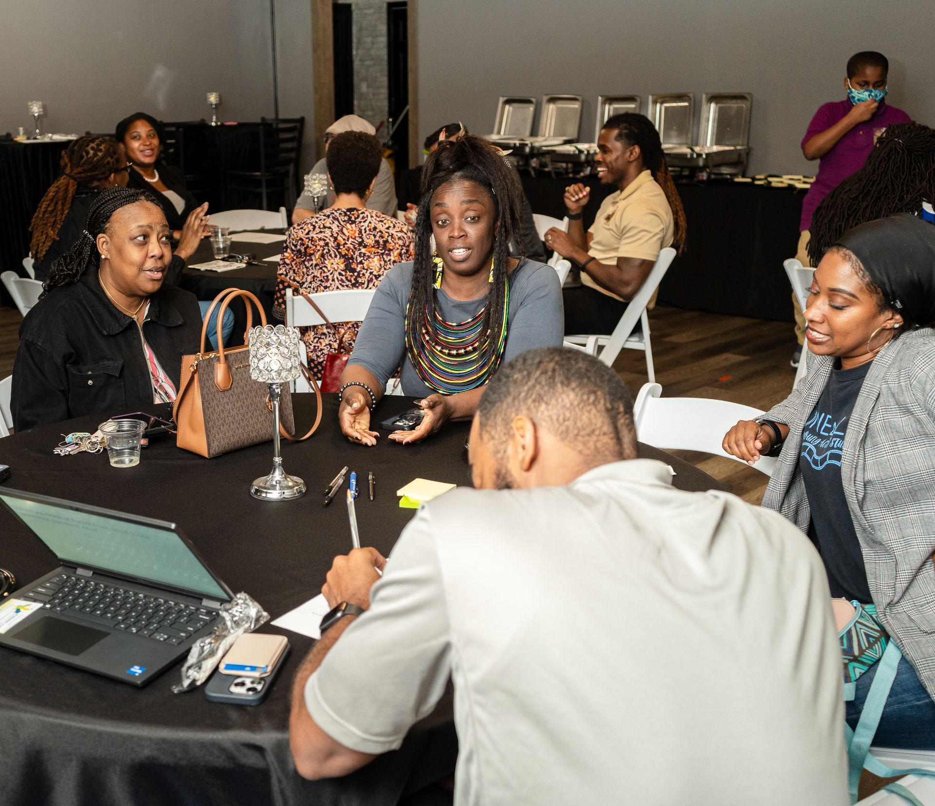 A group of people are sitting around a table with laptops.