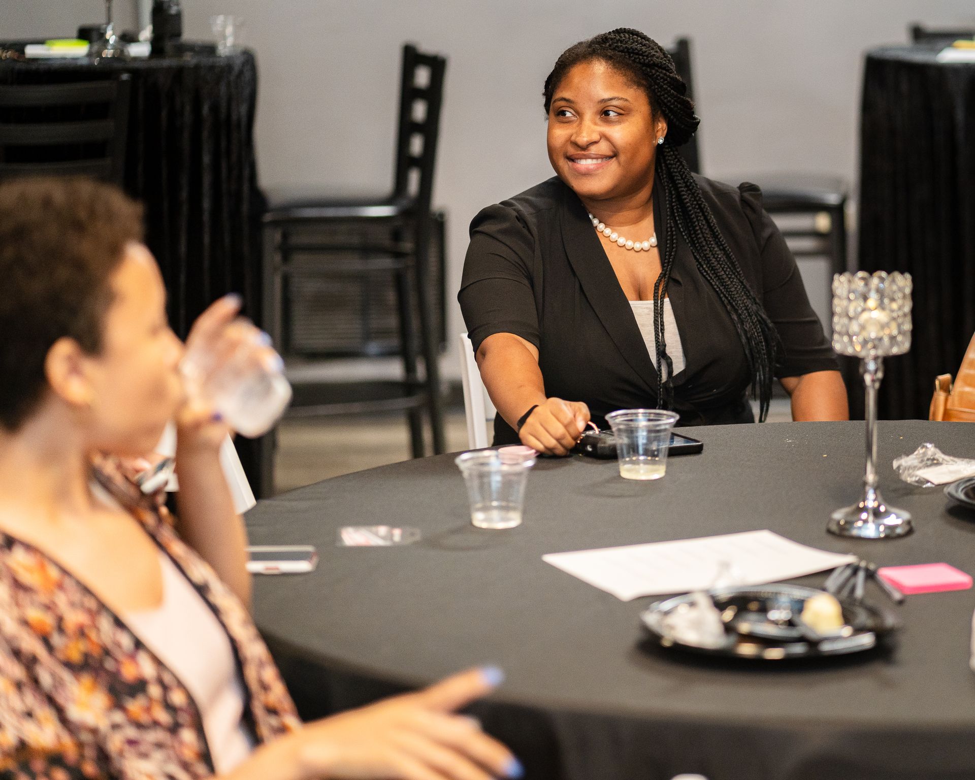 A group of women are sitting at a table drinking water.