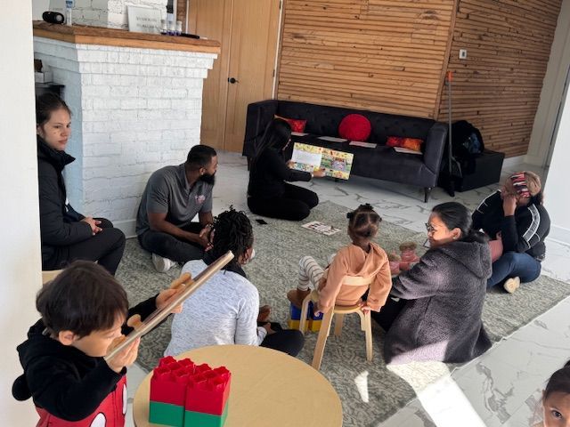 A group of people are sitting around a table in a living room.