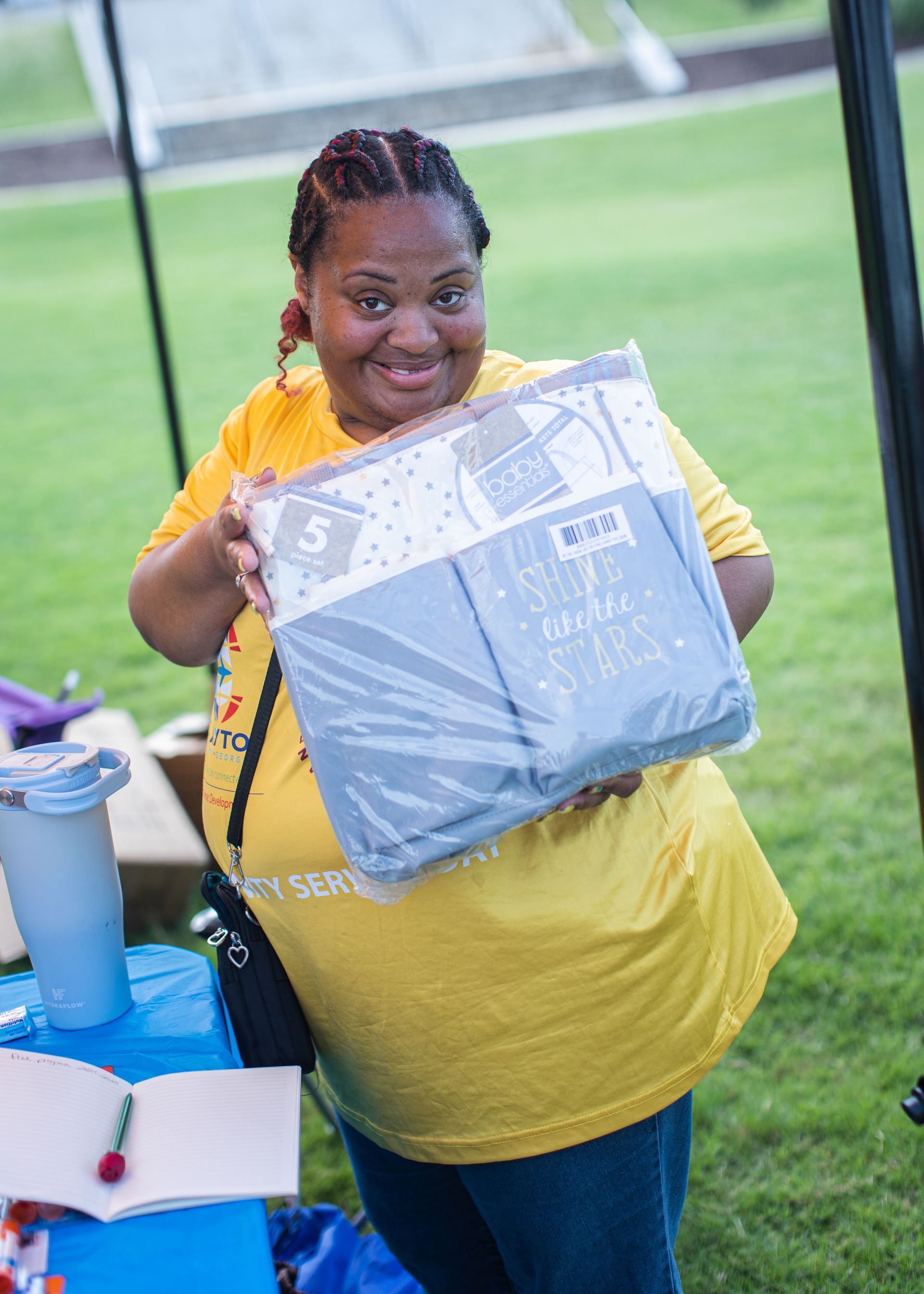 A woman in a yellow shirt is holding a blanket in her hands.