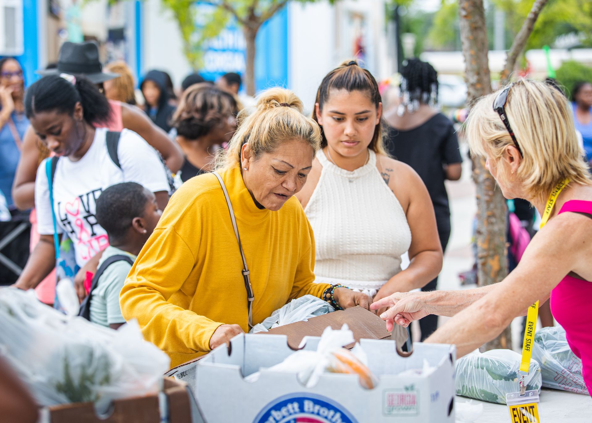 A group of people are standing around a table looking at boxes of food.