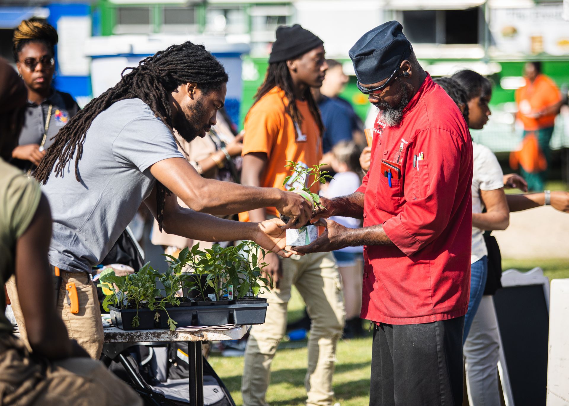 A group of people are standing around a table talking to each other.