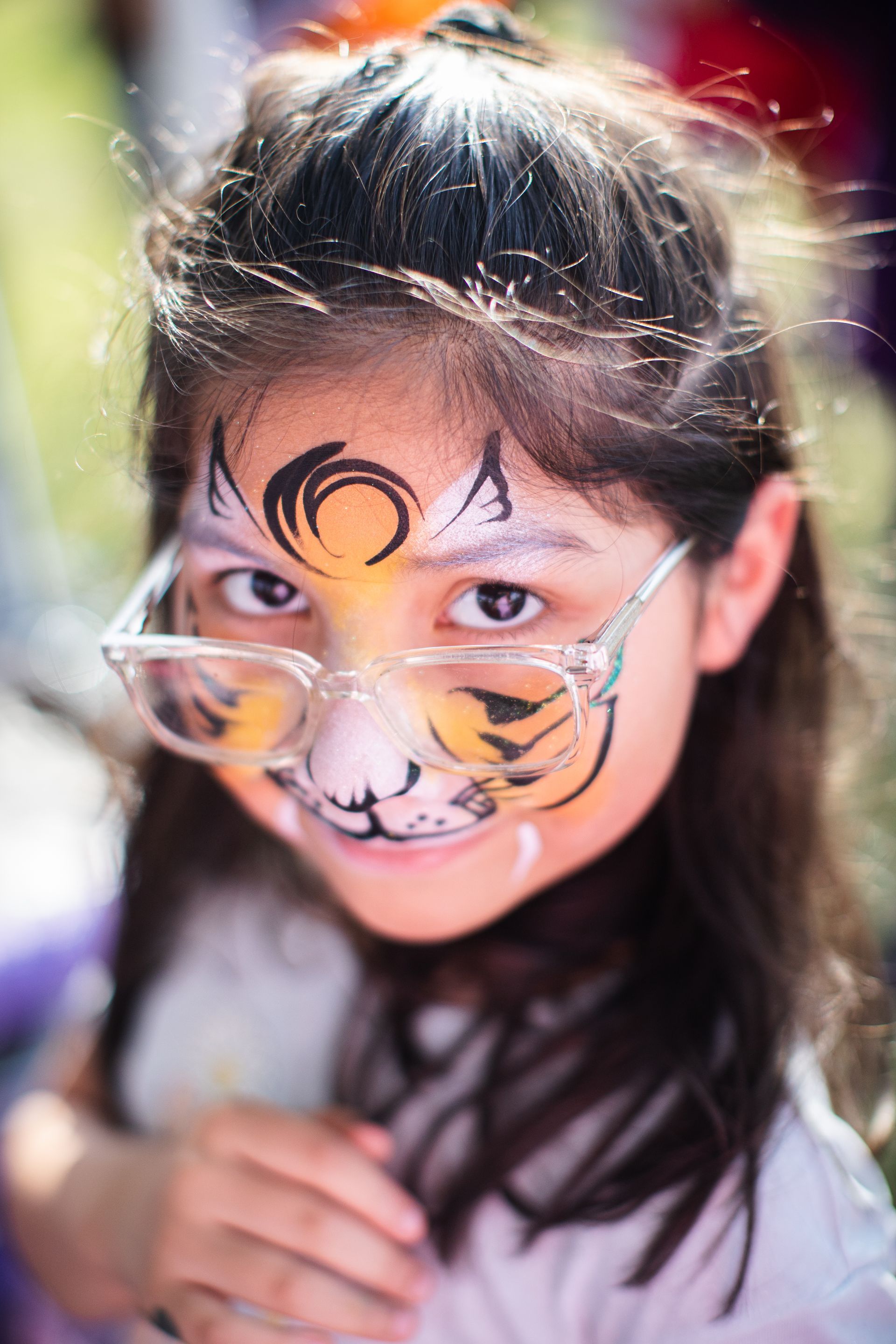 A young girl with her face painted like a tiger.