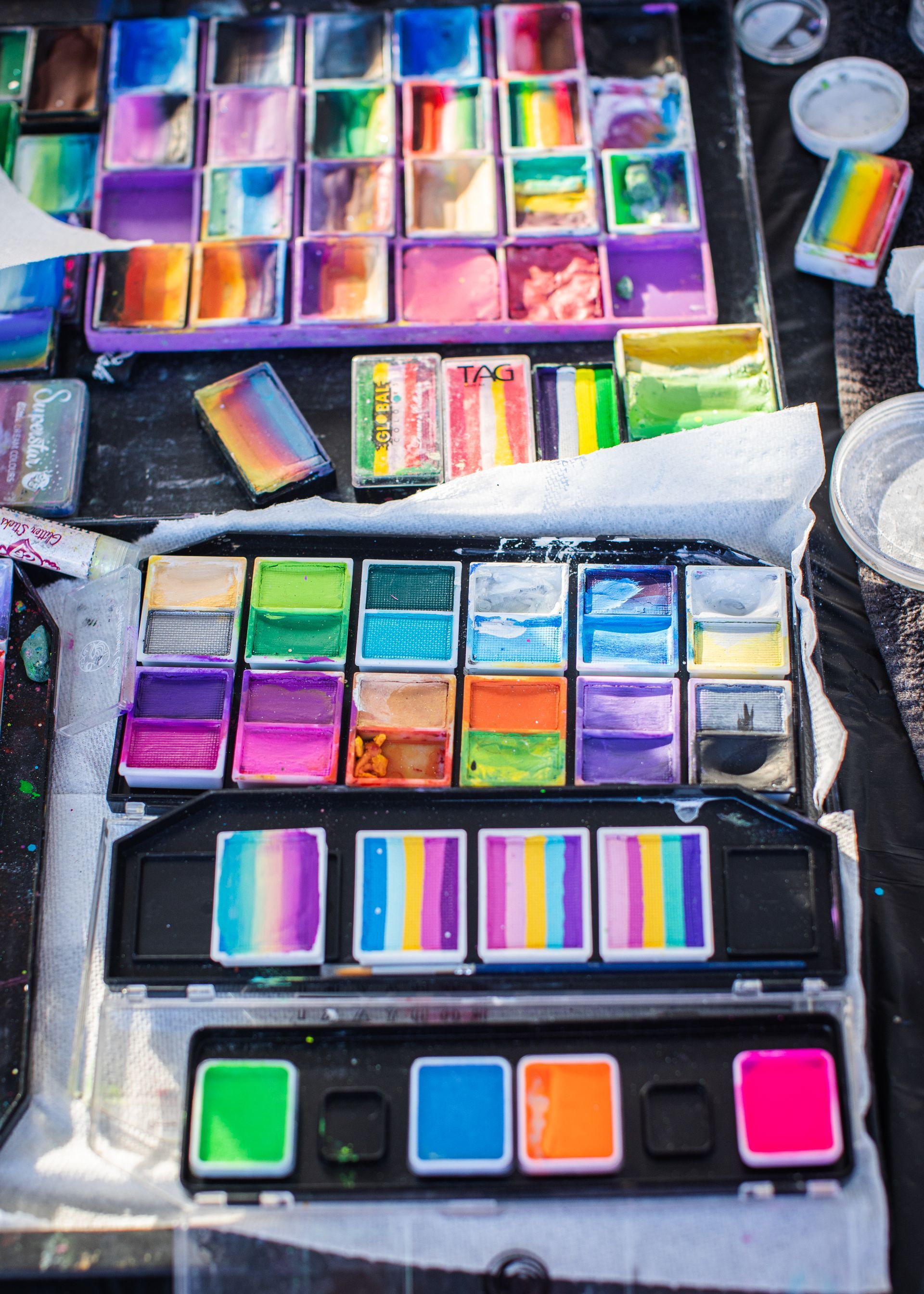 A bunch of different colored face paints are sitting on a table.