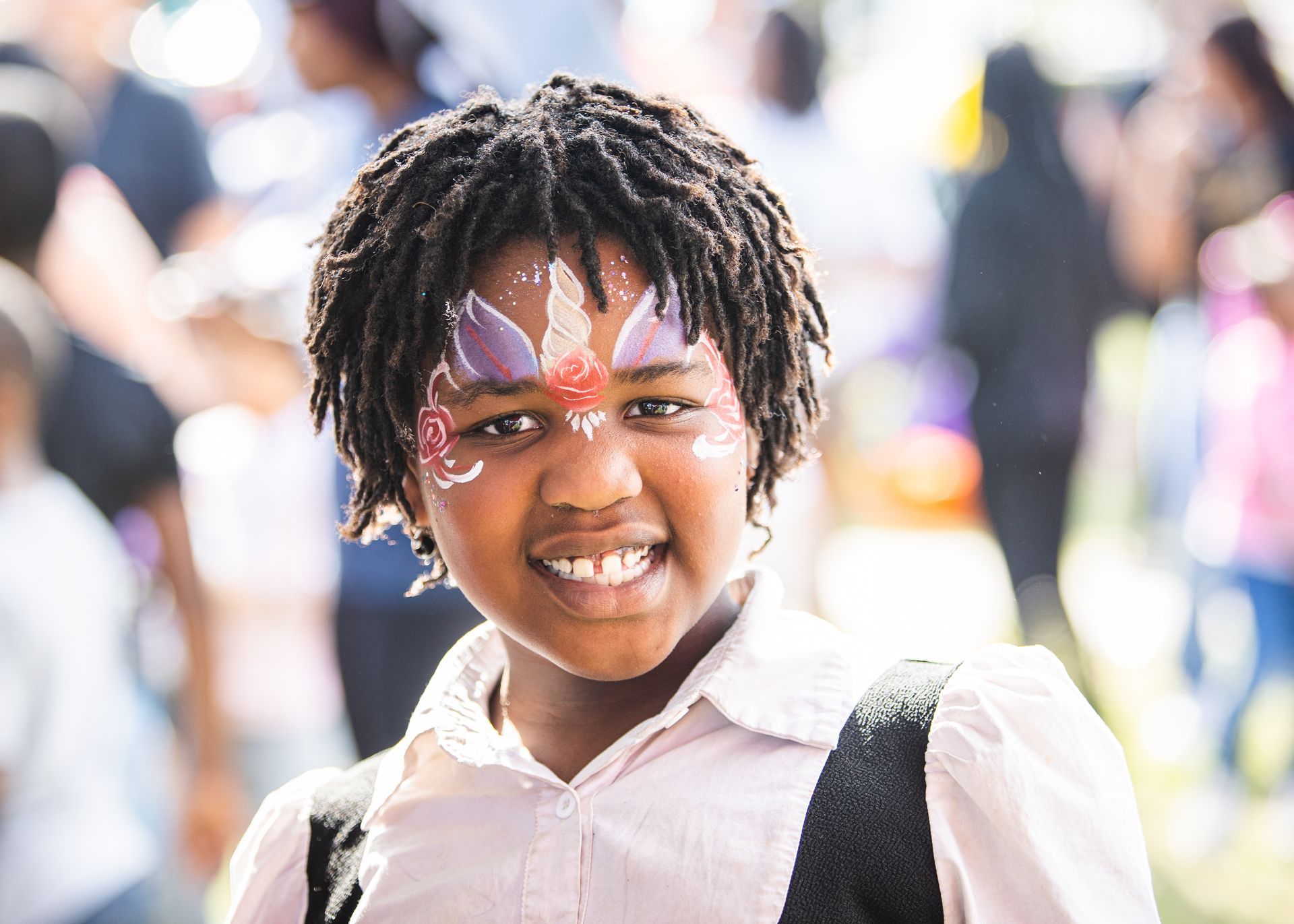 A young girl with face paint on her face is smiling for the camera.